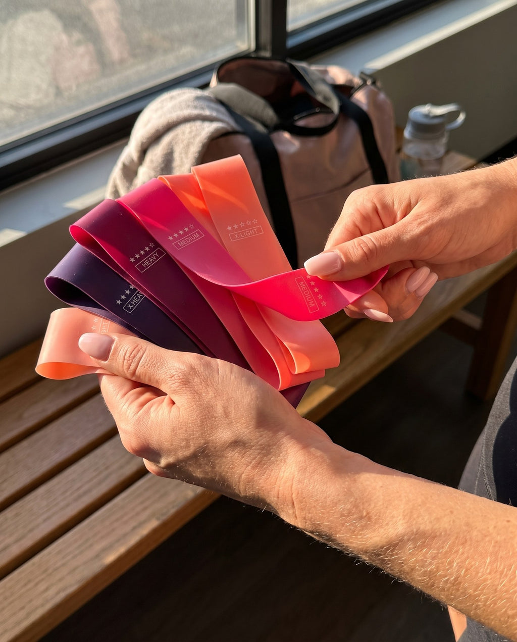 Hands holding the five Blush & Burn resistance bands fanned out
